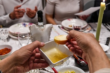 Eine Familie sitzt um einen langen Tisch und feiert Rosch Haschana, das jüdische Neujahrsfest, am 29. September 2019 in Bonn. Eine Schale mit Honig wird weitergereicht, damit jeder Apfelspalten darin eintauchen kann.