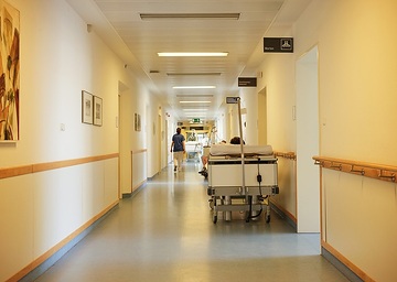 Bett auf einem Flur im Krankenhaus Barmherzige Brüder in Regensburg am 3. August 2022. Eine Krankenschwester geht durch den Gang.