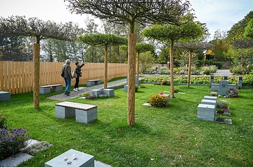 Besucher gehen durch eine Gartenanlage mit Sitzgelegenheiten und fiktiven Gräbern, am 18. Oktober 2023 auf dem "Campus Vivorum" in Süßen.