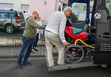 Ein Fahrdienst bringt am 7. November 2023 den schwerstbehinderten Daniel von der Werkstatt nach Hause in Alfter. Vater Günter Gasper hilft, den Rollstuhl aus dem Auto zu heben.