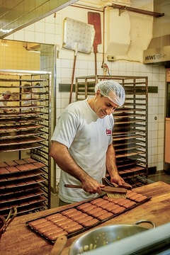 Ein Bäcker bestreicht fertig gebackene Printen mit Kräuterlack am 30. Oktober 2023 in der Printenbäckerei Klein in Aachen.