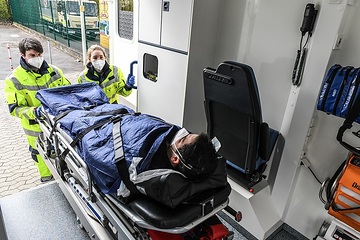 Eine Rettungssanitäterin und ein Rettungssanitäter schieben einen Notfallpatienten auf einer Trage in den Rettungswagen während einer Übung in Bonn am 17. April 2021.
