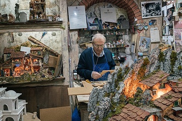 Ein Mann steht in seiner Werkstatt und arbeitet an einer Krippe am 20. November 2021 in der Via San Gregorio Armeno in Neapel. Um ihn herum stehen weitere Krippen.