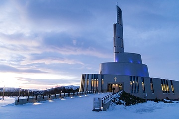 Wolken ziehen über die evangelisch-lutherische Nordlichtkathedrale am 17. Dezember 2023 in Alta (Norwegen). Der Himmel leuchtet purpur und blau.