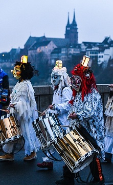 Mitglieder einer Fasnachtsclique gehen mit Trommeln im Morgengrauen über die Mittlere Brücke während des Morgenstreichs am 19. Februar 2018 in Basel. Im Hintergrund ist das Basler Münster zu sehen.