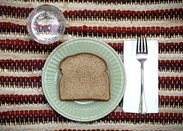 Eine Scheibe Brot auf einem Teller und ein Glas Wasser, am 12. Januar 2024 in Prescott (USA).