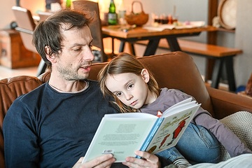 Vater und Sohn sitzen am 6. März 2024 auf dem Sofa zuhause in Rheinbach. Der Vater liest dem Jungen aus dem Buch "Die Häschenschule" vor.