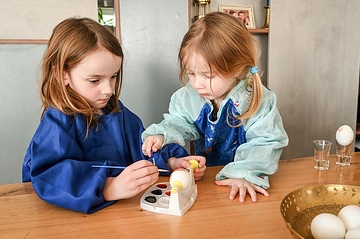 Ein Junge (l.) und ein Mädchen sitzen am 6. März 2024 am Wohnzimmertisch zuhause in Rheinbach und malen gekochte Eier an zu Ostern.