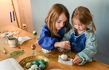 Ein Junge (l.) und ein Mädchen sitzen am 6. März 2024 am Wohnzimmertisch zuhause in Rheinbach und malen gekochte Eier an zu Ostern.