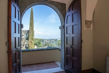 Blick durch ein Eingangsportal der päpstlichen Sommerresidenz in Castel Gandolfo (Italien) in die Gärten auf dem Gelände der Päpstlichen Villen am 23. März 2024.