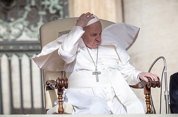 Papst Franziskus hält mit einer Hand seinen Pileolus auf seinem Kopf während einer windigen Generalaudienz am 10. April 2024 auf dem Petersplatz im Vatikan.