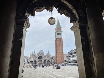 Blick durch einen Torbogen am 16. April 2024 auf den Markusplatz mit Markusdom (Basilica di San Marco) und Markusturm in Venedig (Italien).