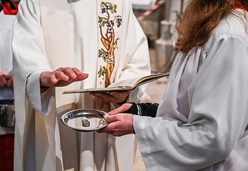 Ein Priester segnet die Eheringe des Brautpaars, die auf einem silbernen Tablett liegen, am 20. April 2024 in der Kirche Sankt Laurentius in Bad Neuenahr-Ahrweiler.