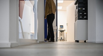 Eine Patientin geht in ein Sprechzimmer in einer Arztpraxis am 21. Dezember 2022 in Bonn. Im Hintergrund steht in einem weiteren Untersuchungsraum ein Ultraschallgerät.